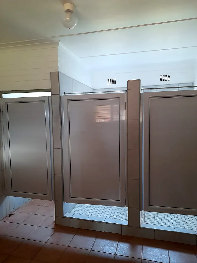 Bronze aluminium cubicle doors in a tiled bathroom